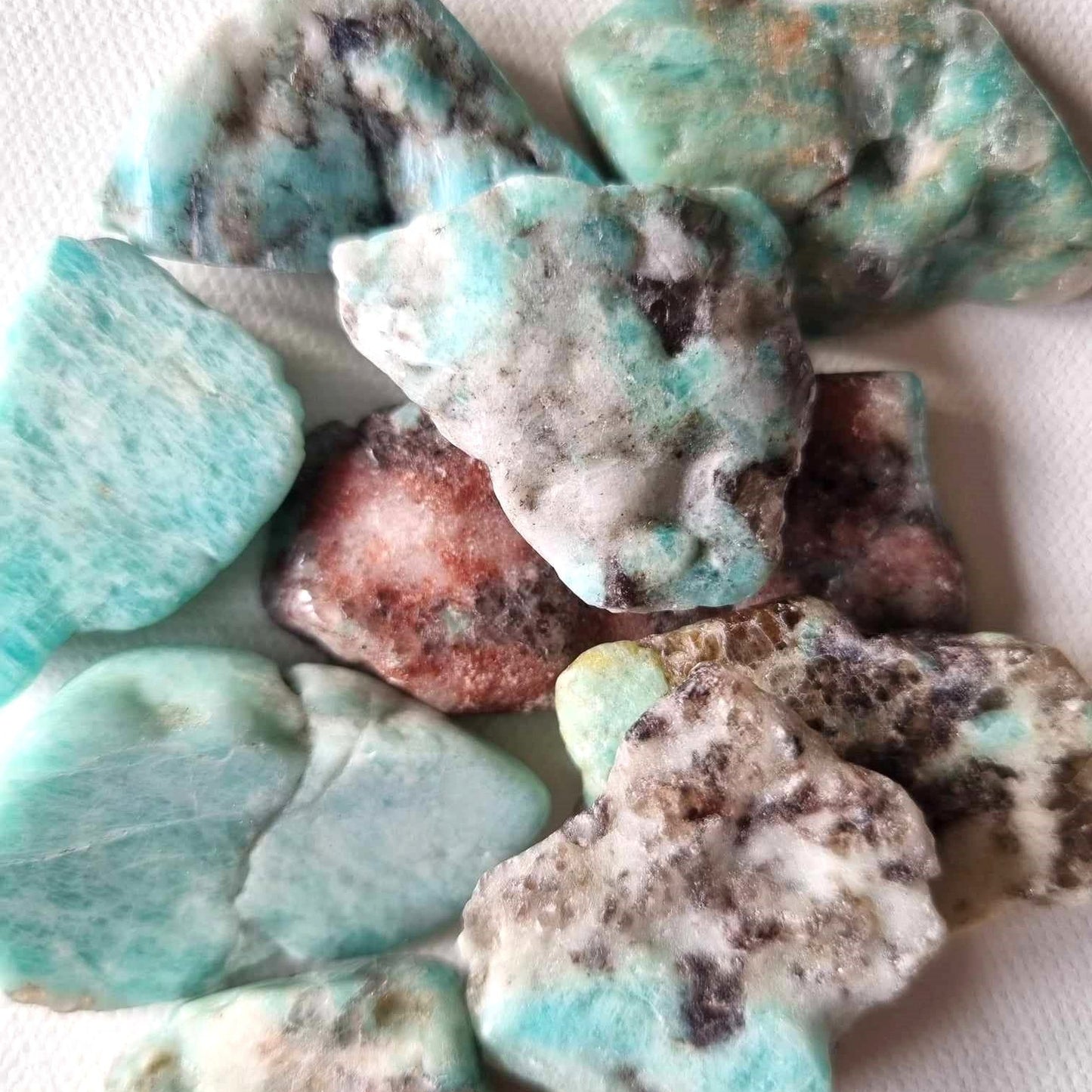 Collection of turquoise and brown raw gemstones on a white background