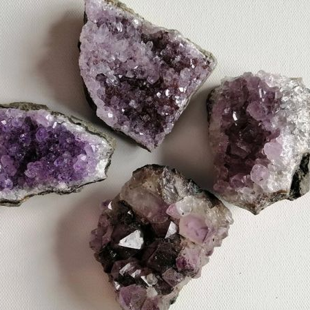 Four amethyst crystal formations on a light background