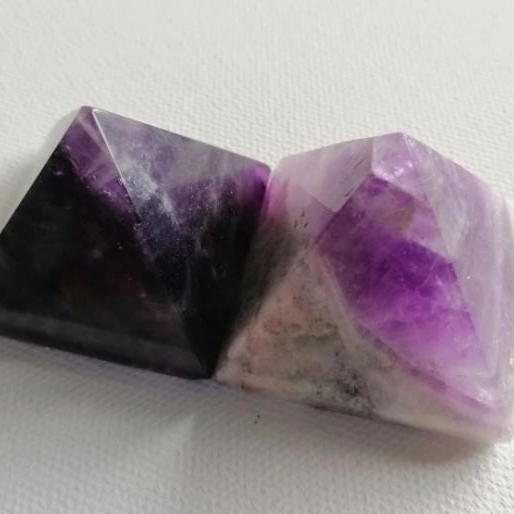 Two purple pyramid shaped crystals on a white background