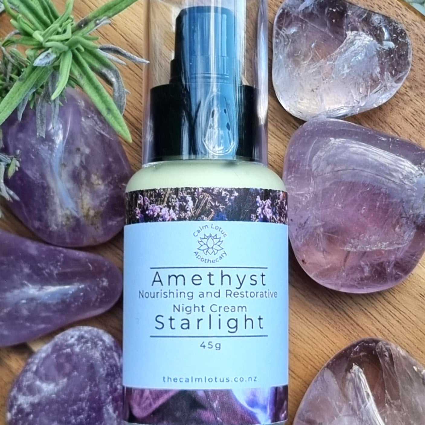 Amethyst night cream bottle labeled 'Starlight' surrounded by amethyst stones on a wooden surface.