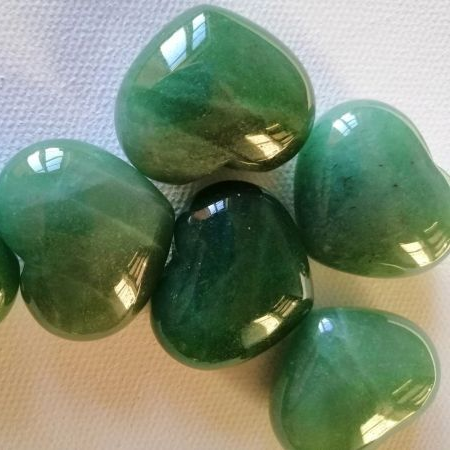 Green heart-shaped stones on a textured white surface