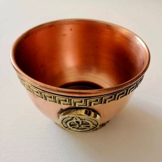Copper bowl with intricate designs on a white background