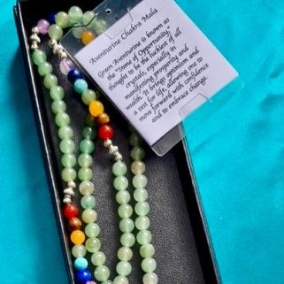 Colorful mala beads with a pendant on a black card against a blue background