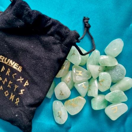 Green crystal runes with a black drawstring bag on a blue background