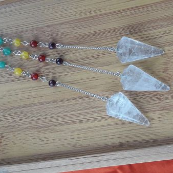 Crystal pendulums with chakra beads on a wooden surface