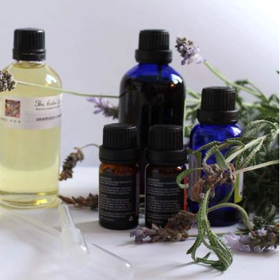 Collection of essential oil bottles with labels and lavender flowers on a white background