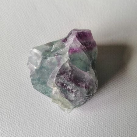 Crystal with purple and green colors on a white background