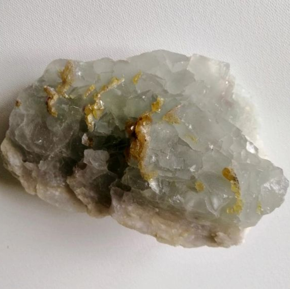 Raw Fluorite piece with gold vein on a white background