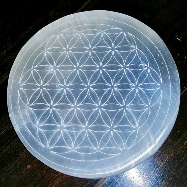 Selenite with Flower of Life pattern on a dark surface