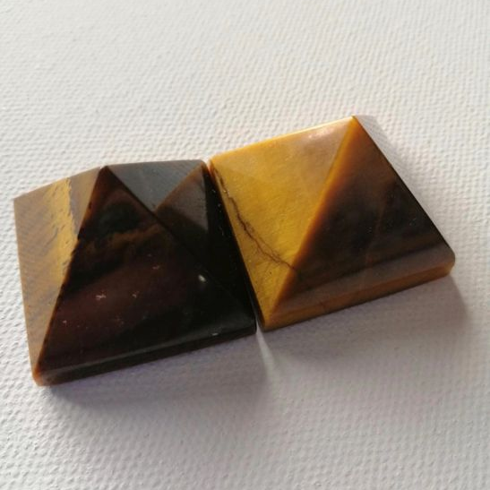 Two pyramid shaped brown stones on a white fabric background