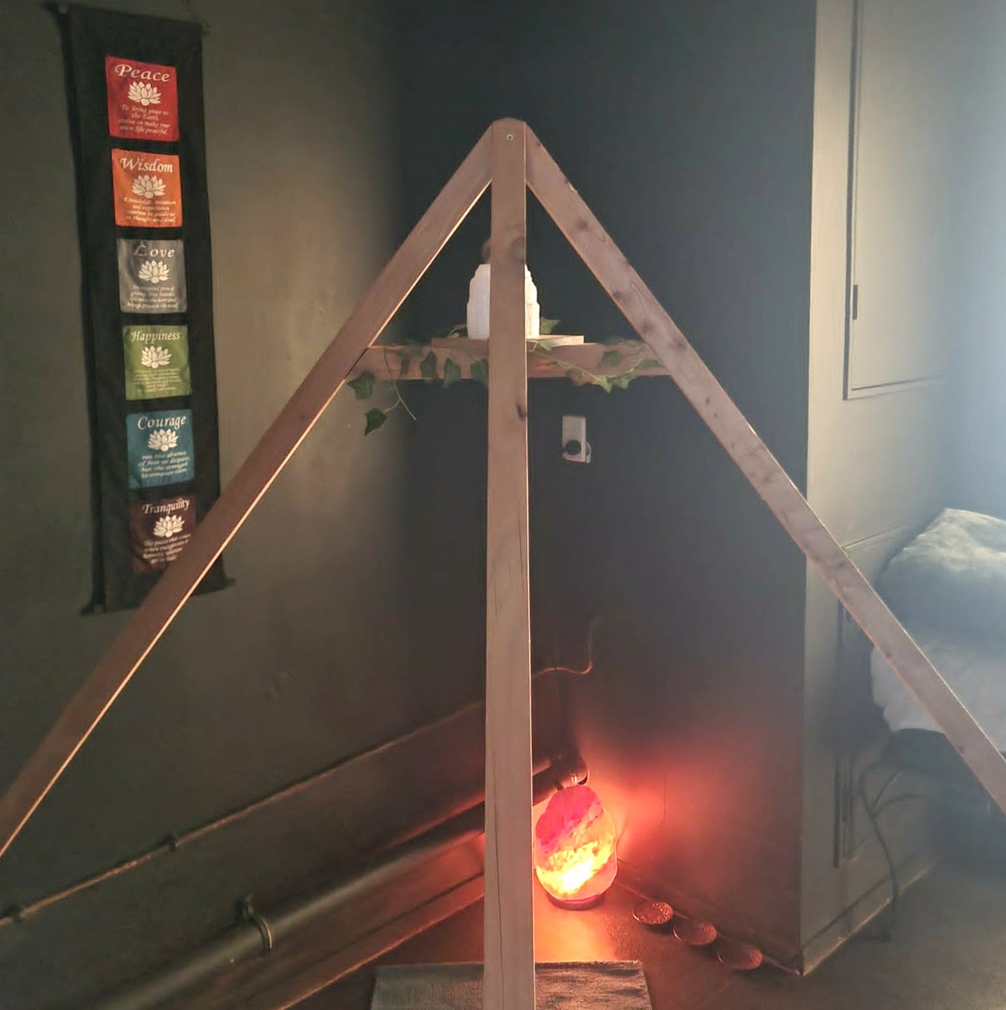 Wooden pyramid structure with a glowing salt lamp inside, in a dimly lit room.