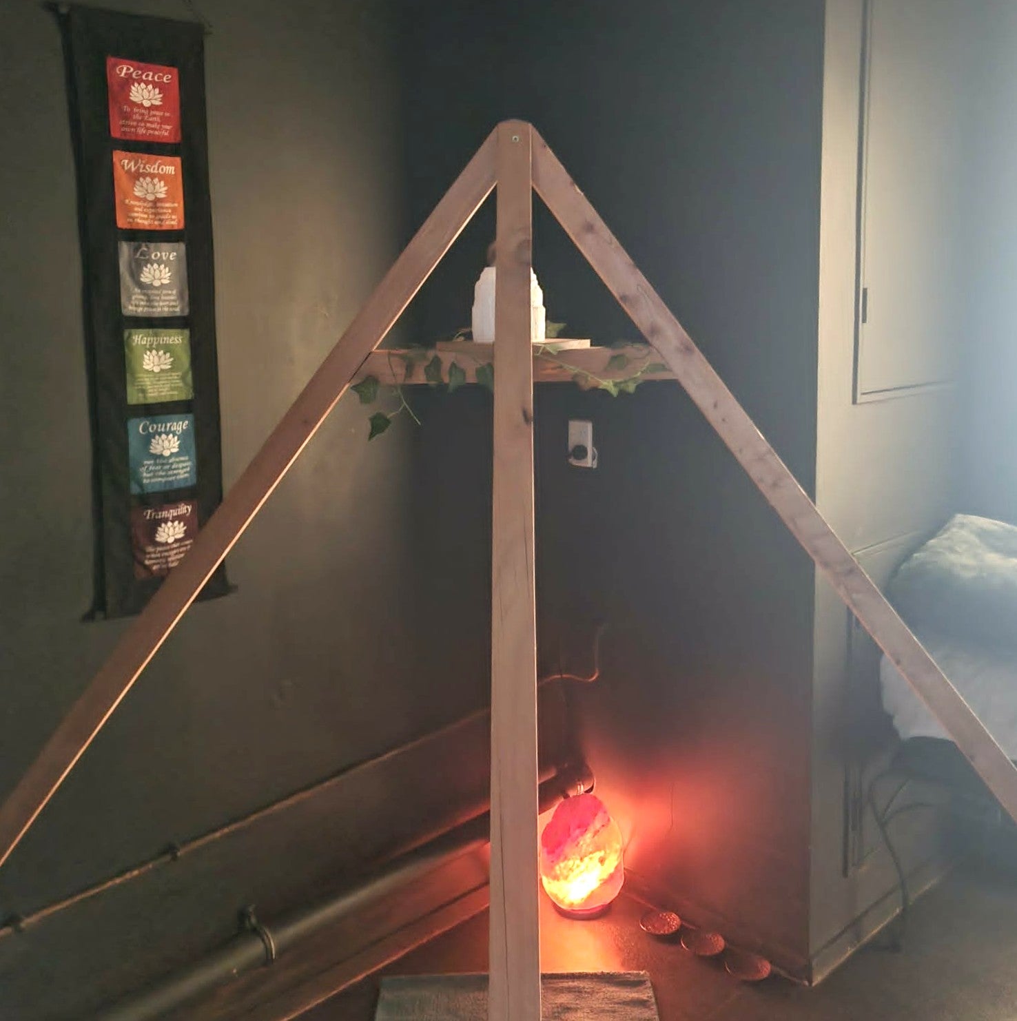 Wooden pyramid structure with a glowing salt lamp inside, in a dimly lit room.