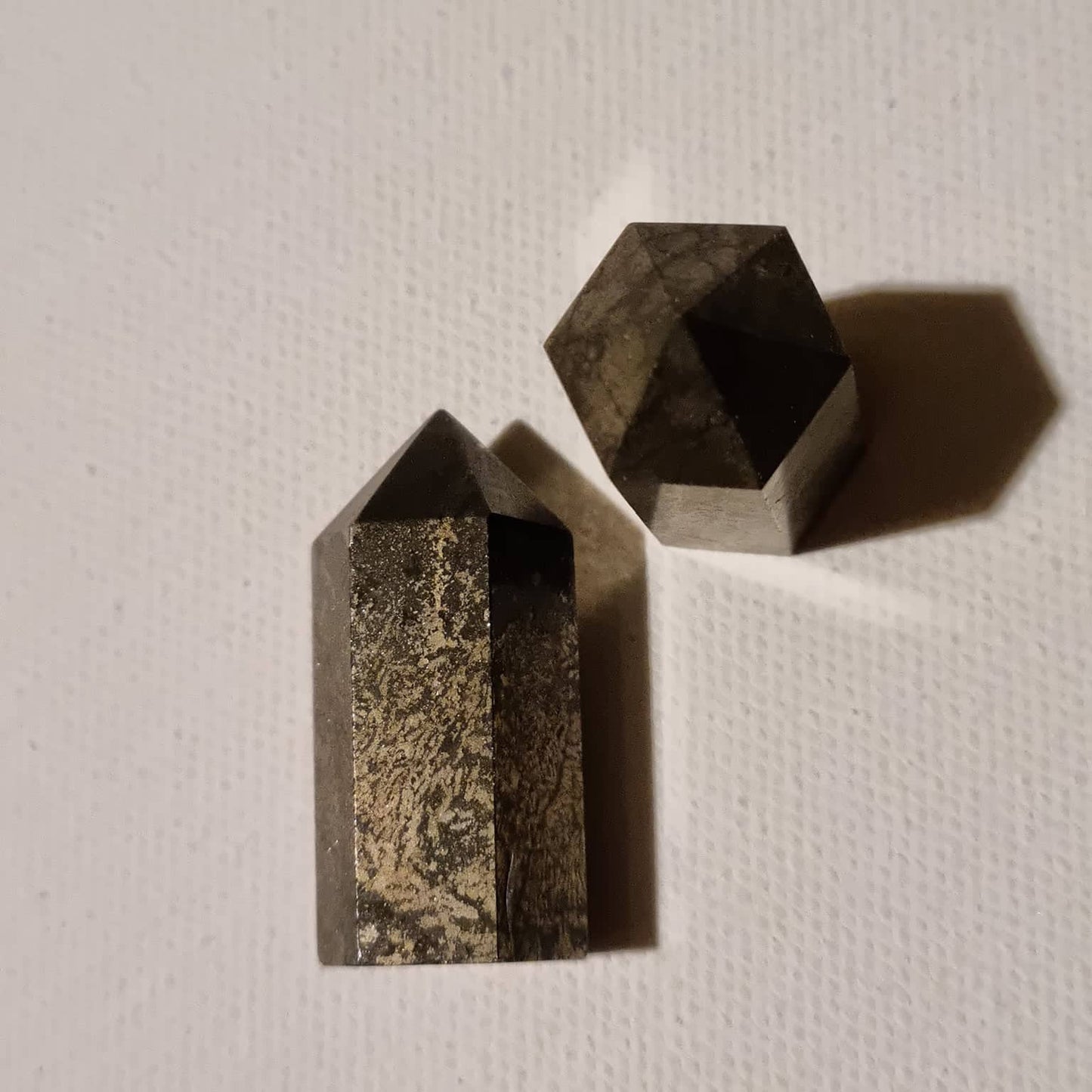 Two crystal points on a textured white surface