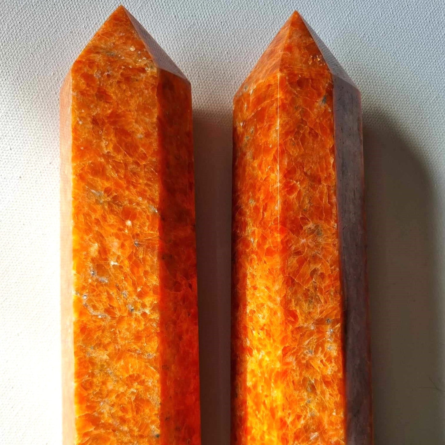 Two orange crystal points on a light gray background