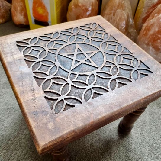 Wooden stool with intricate cut-out design on a carpeted floor.