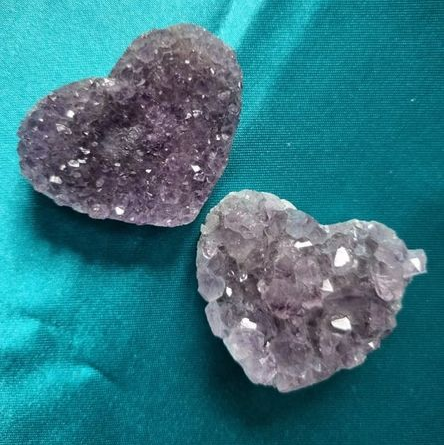 Two heart-shaped crystal rocks on a teal fabric background