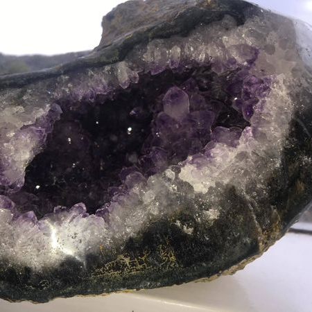 Amethyst geode with a dark purple interior and white exterior on a white background