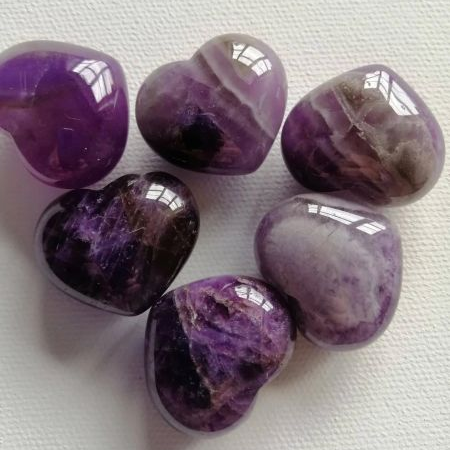 Purple heart-shaped stones on a white fabric background