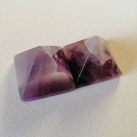 Polished purple pyramid shaped stones on a white background