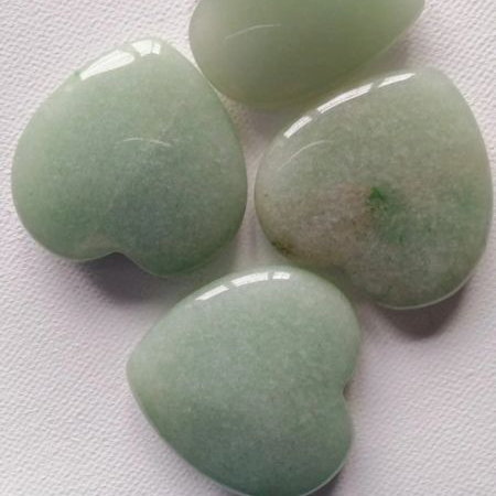 Four green heart-shaped stones on a white background