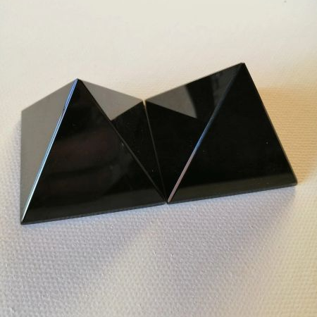 Black pyramid shaped crystals on a textured white surface