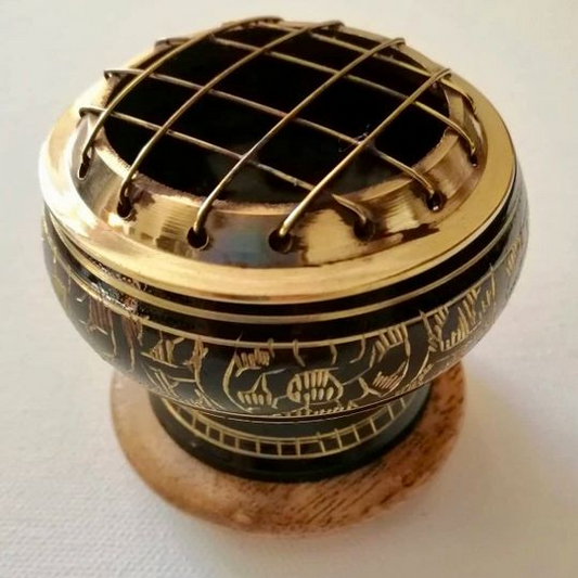 Decorative metal incense holder with intricate designs on a white background