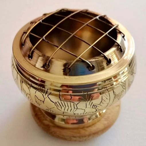Brass incense burner with engraved designs on a white background