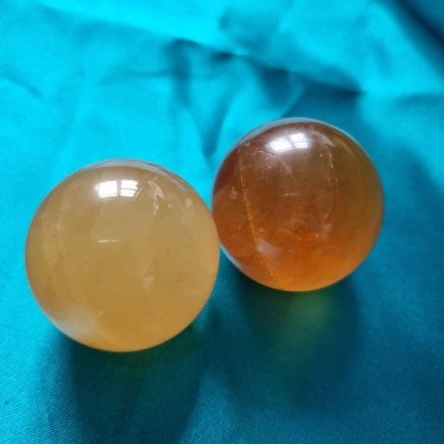 Two orange crystal balls on a blue fabric background