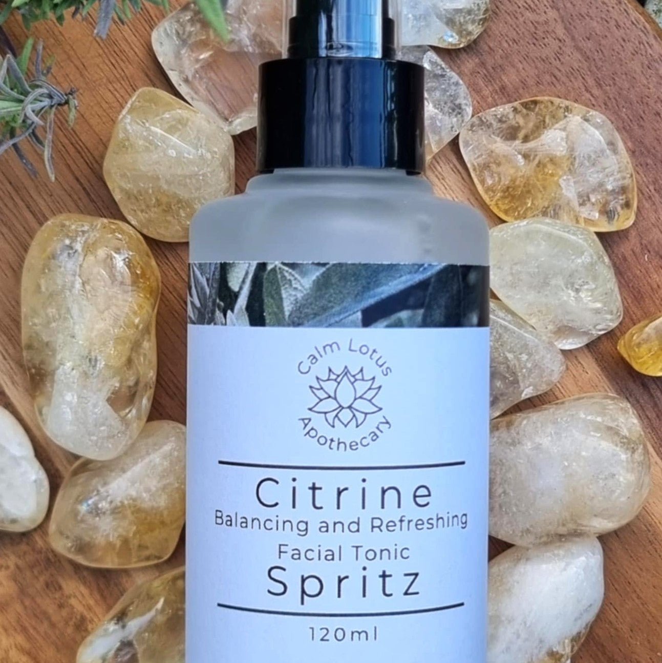 Facial tonic spritz bottle labeled 'Citrine' on a wooden surface with crystals and herbs.