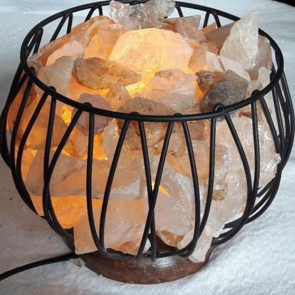 Decorative lamp with crystal stones inside a black wire cage on a white surface
