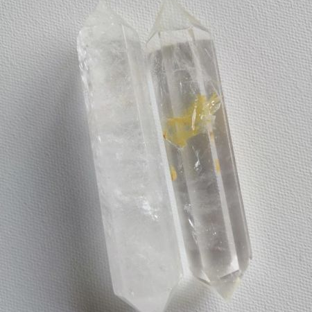 Clear crystal wands, one with a yellow inclusion, on a white background