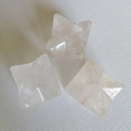 Three star-shaped white stones on a textured white surface