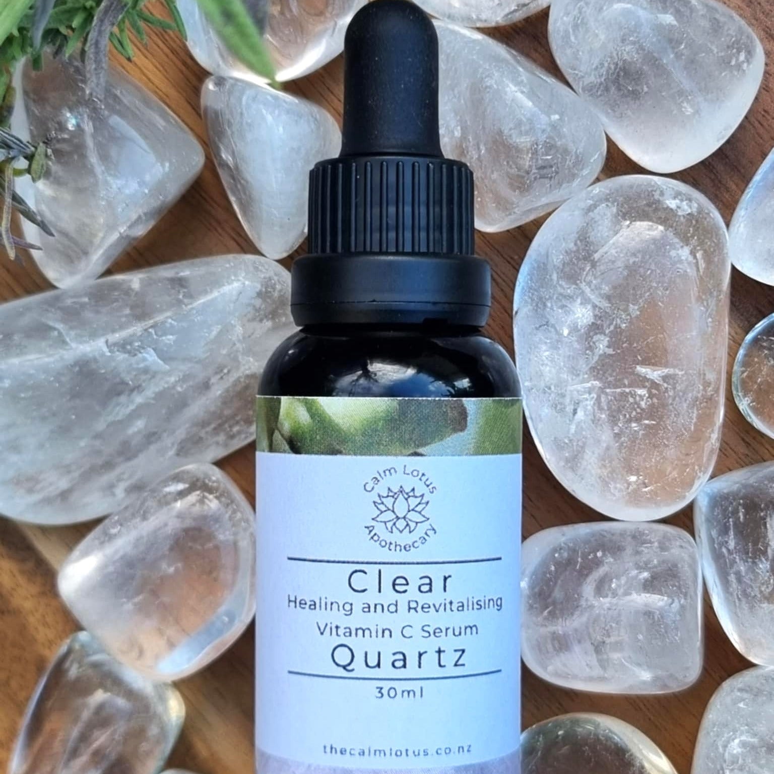 Bottle of Clear Healing and Revitalizing Vitamin C Serum Quartz on a wooden surface with crystals.