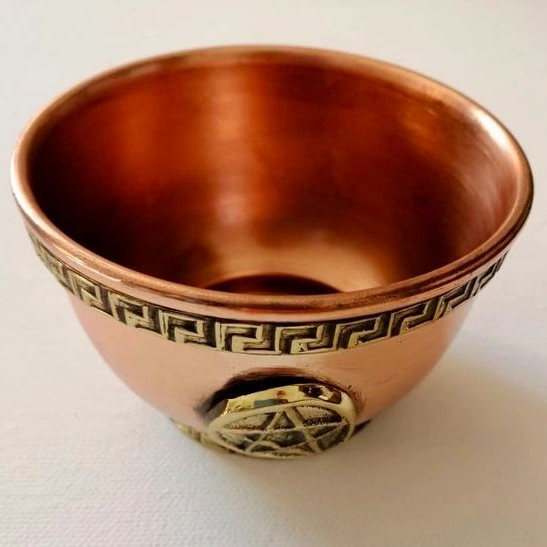 Copper bowl with intricate designs on a white background