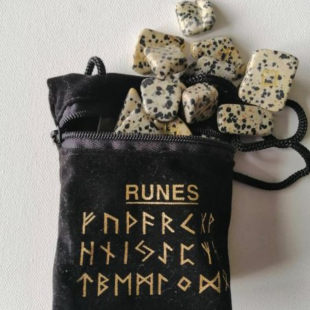 Black pouch with gold runes text and stones on a white background