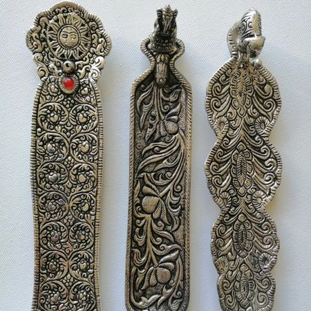 Three ornate metal incense holders with intricate designs on a white background