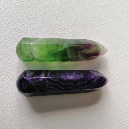 Two crystal wands, one green and one purple, on a white background