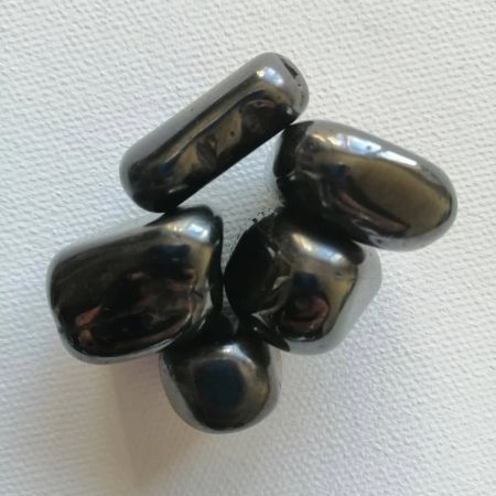 Five shiny black pieces of magnetic Hematite on a white background