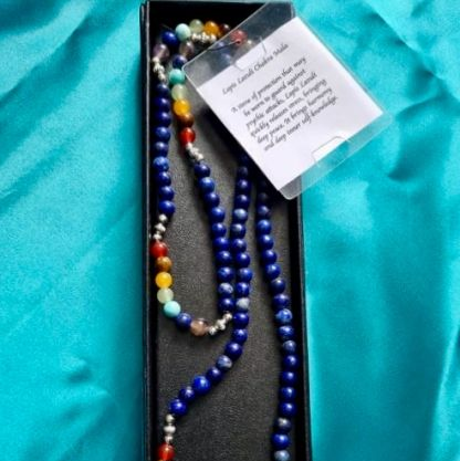 Colorful mala beads with a card on a turquoise fabric background