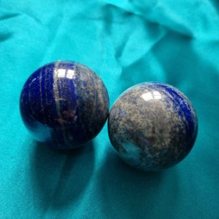 Two lapis orbs on a teal fabric background