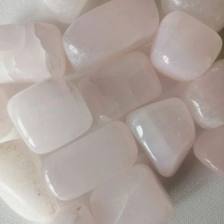 Close-up of pink calcite tumble stones on a textured surface