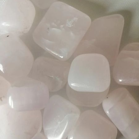 Calcite tumble stones on a textured white background
