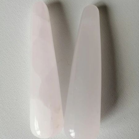 Two pinkish calcite wands on a light gray background