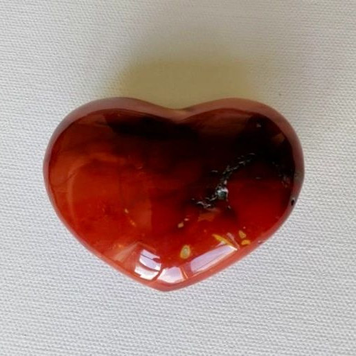 Heart-shaped red stone on a white fabric background