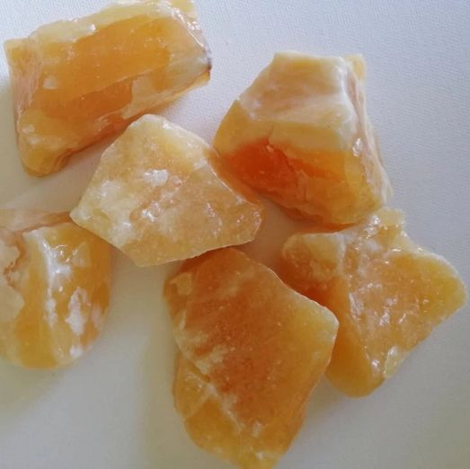 Raw orange calcite pieces on a white background