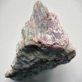 Raw pink tourmaline piece on a gray background
