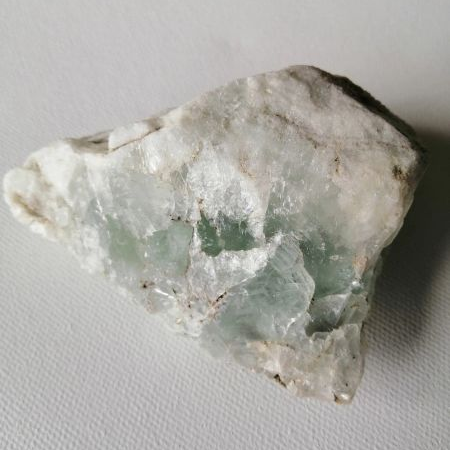 Fluorite raw piece on a light gray background