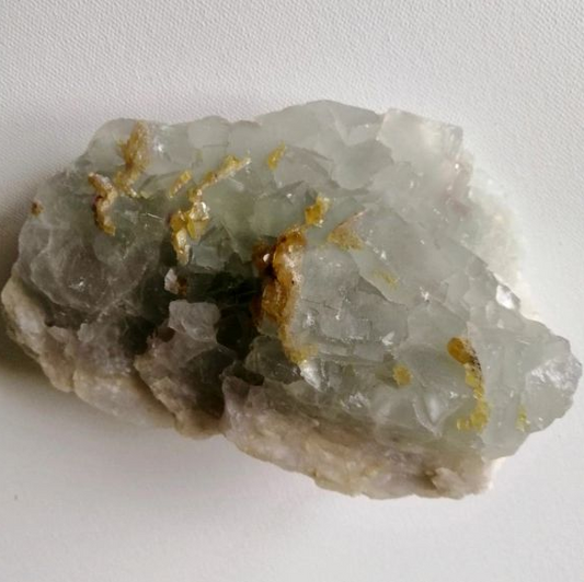 Raw Fluorite piece with gold vein on a white background
