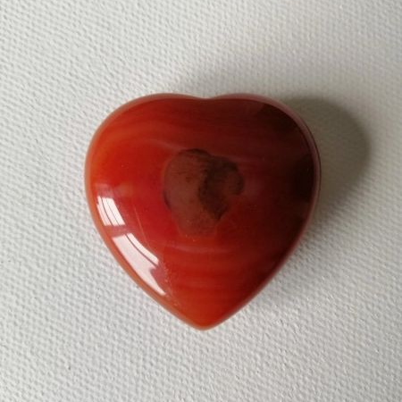 Heart-shaped red stone on a white background