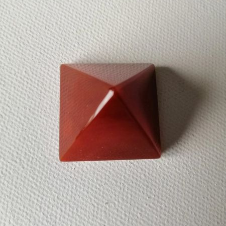 Red pyramid-shaped object on a textured white surface